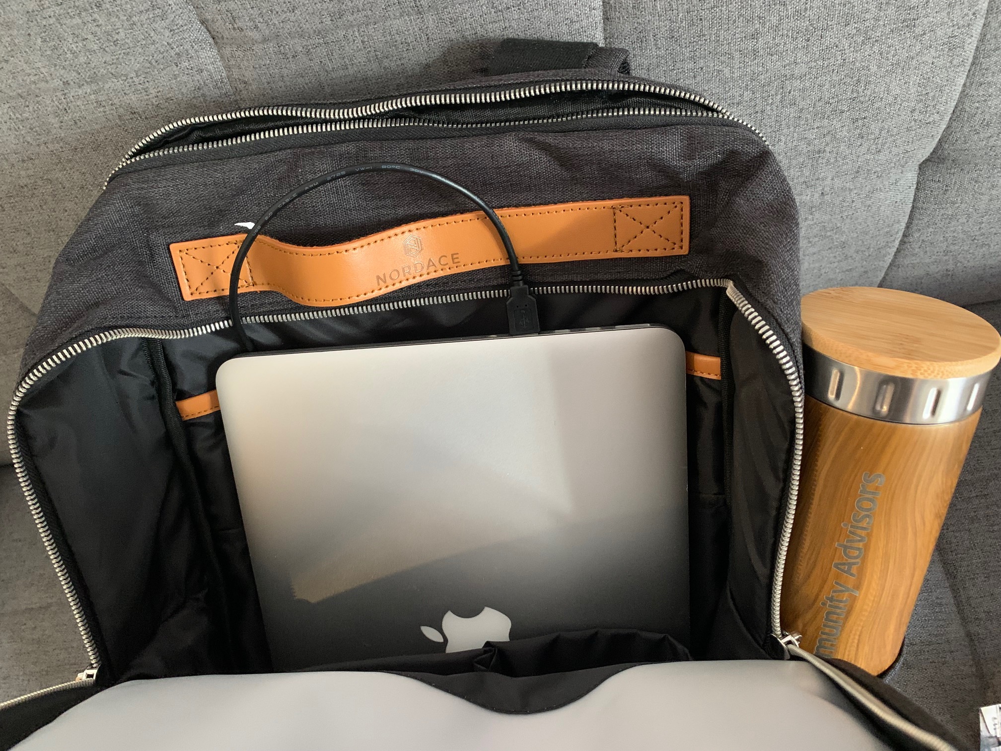 The Nordace backpack with its charging port to a Macbook